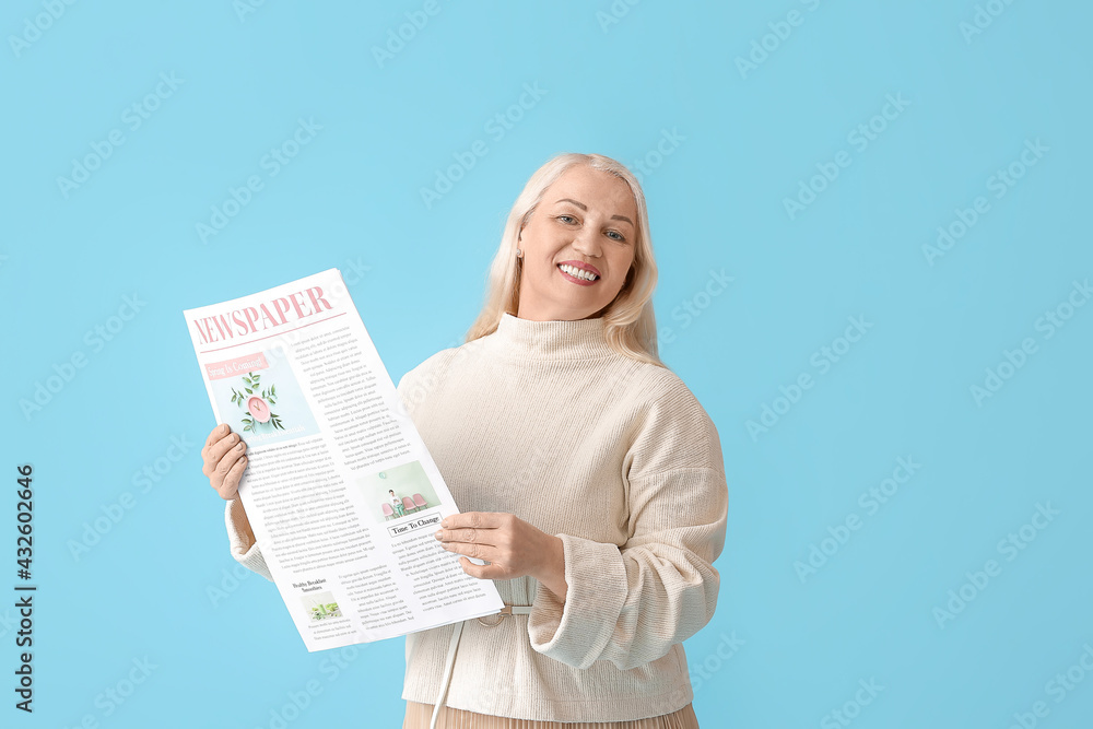 Mature woman with newspaper on color background