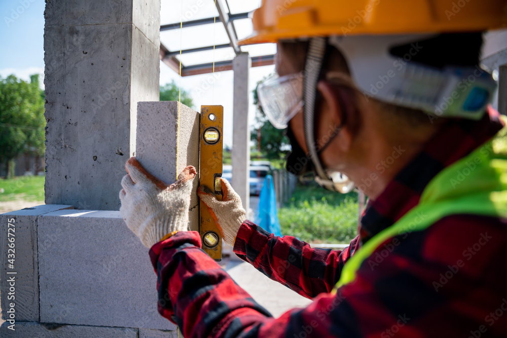 Close-up bricklayer builder  using the water level, check the inclination of autoclaved aerated conc