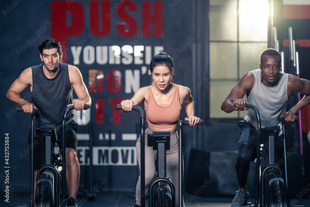 Group of multiethnic fitness trainer performing exercise by air bike.