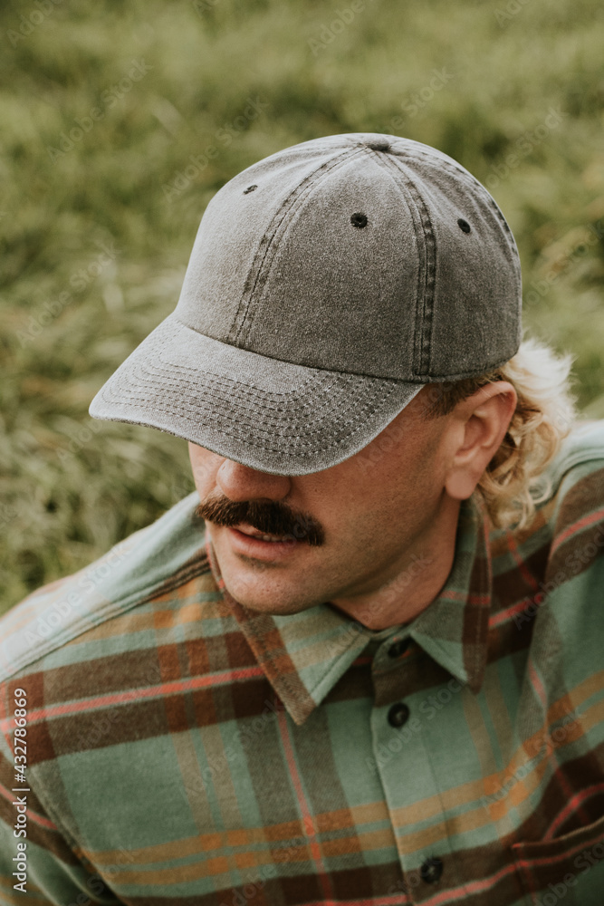 Man with mustache wearing a cap and green flannel shirt