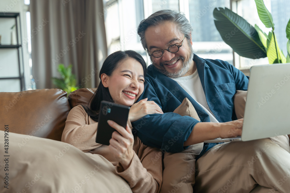 Happy Female showing smartphone to husband in living room at home