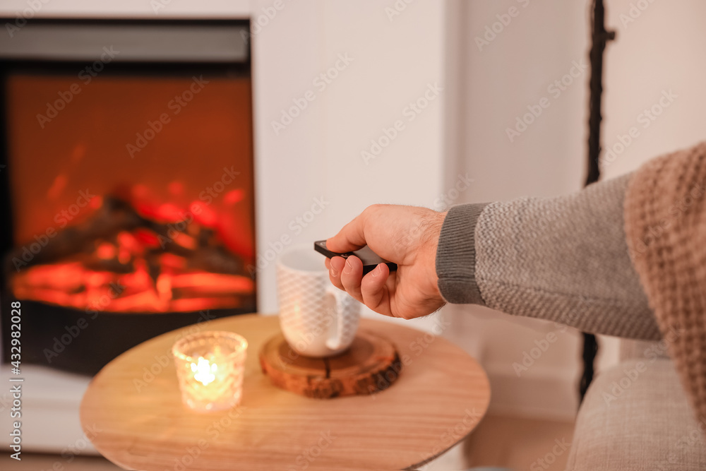 Man adjusting electric fireplace at home