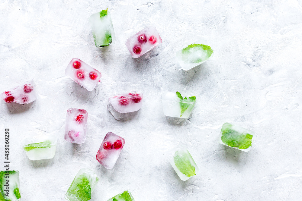 ice cubes with red berries and mint top view gray stone background mockup