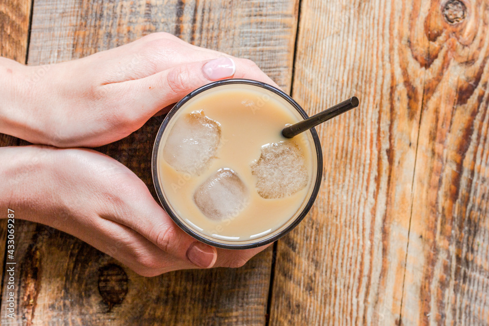 iced coffee in hands for cold summer drink on white background top view