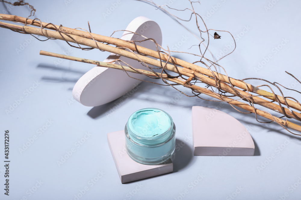 Jar of cosmetic clay on light background