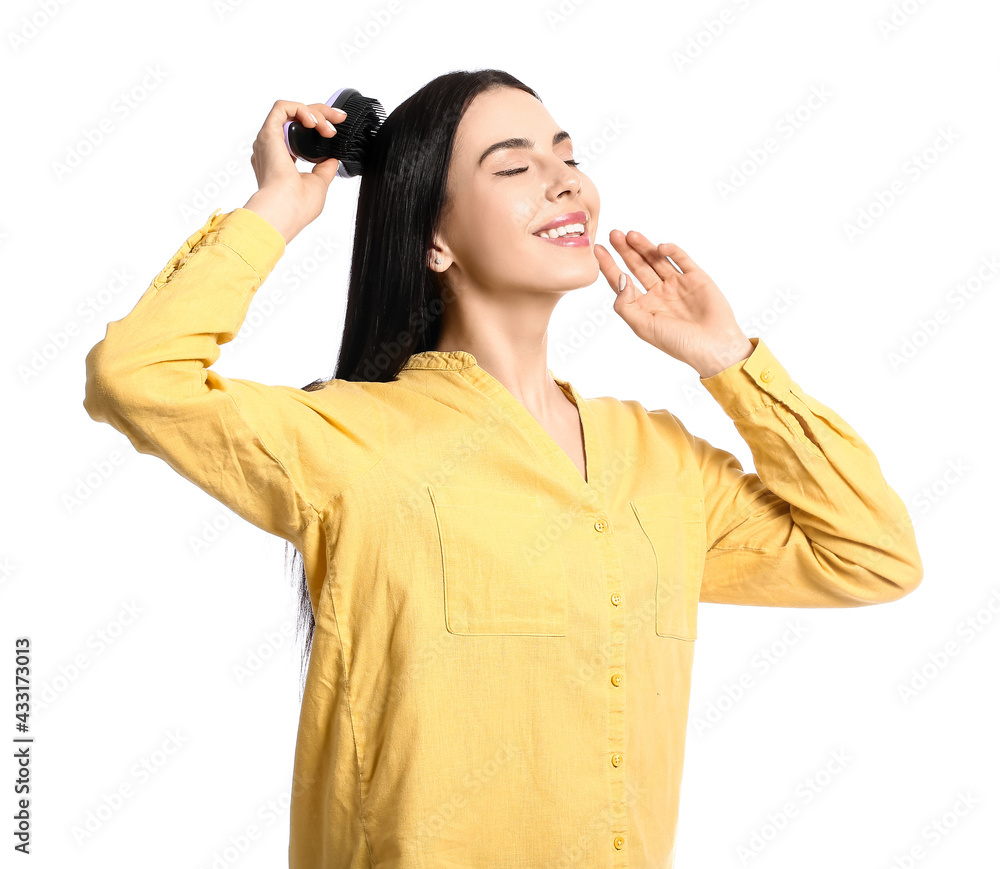 Beautiful young woman with hair brush on white background