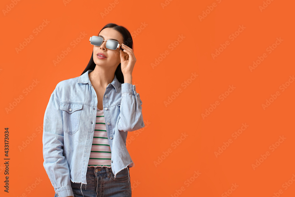 Beautiful young woman wearing stylish sunglasses on color background