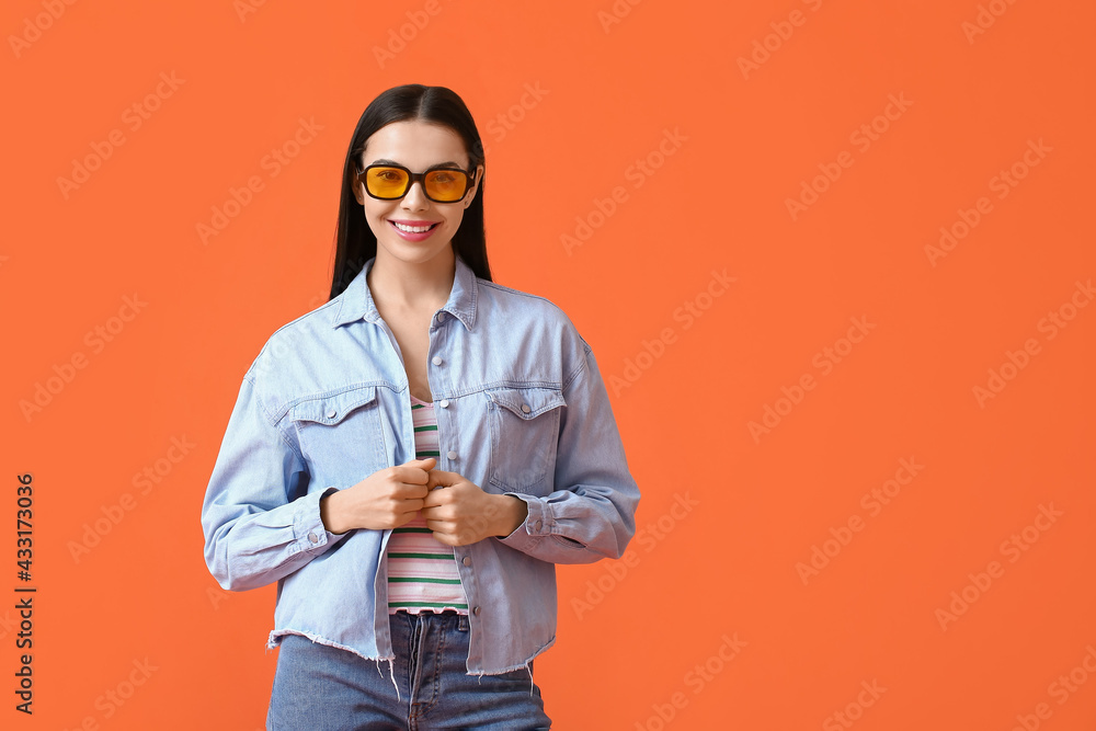 Beautiful young woman wearing stylish sunglasses on color background