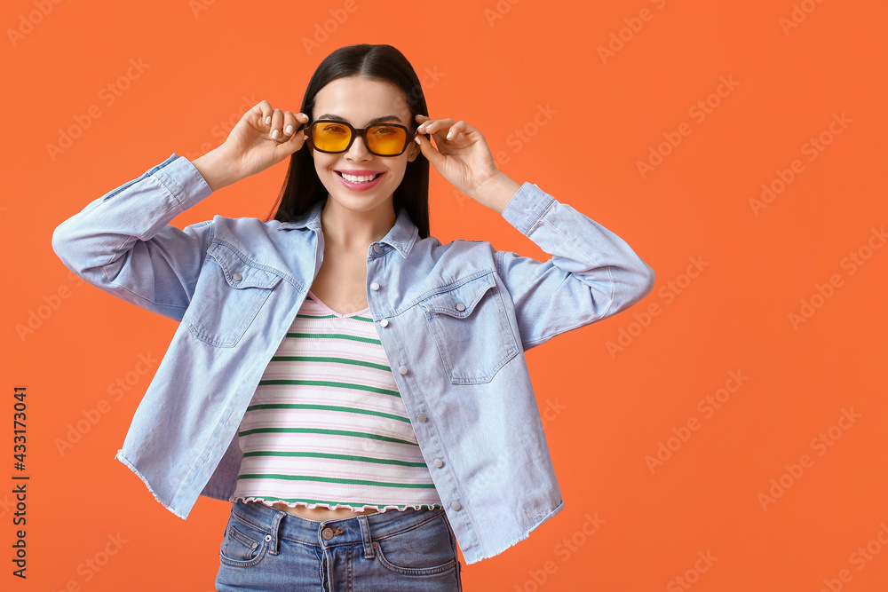 Beautiful young woman wearing stylish sunglasses on color background