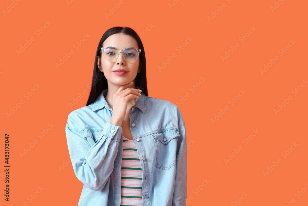 Beautiful young woman wearing eyeglasses on color background