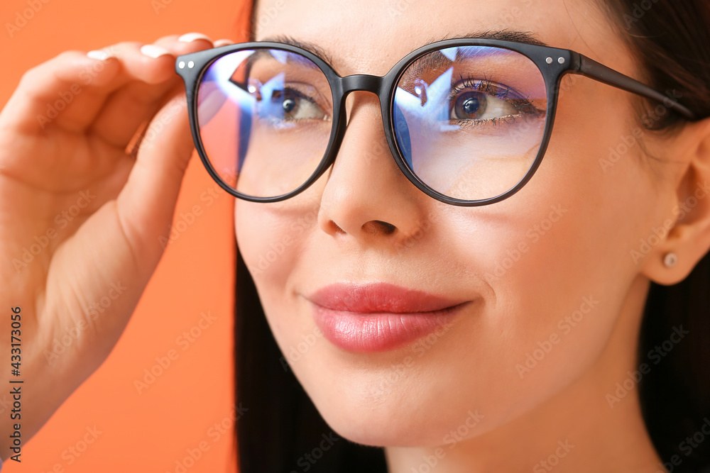 Beautiful young woman wearing eyeglasses on color background, closeup