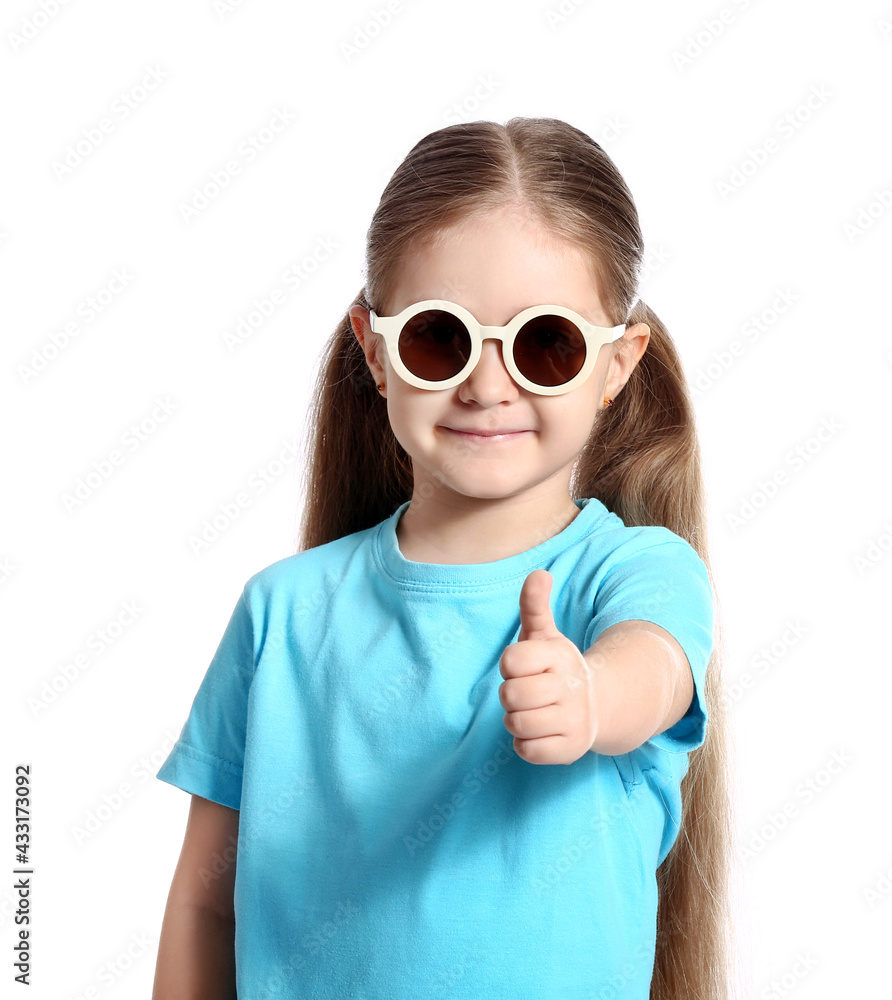 Cute little girl wearing stylish sunglasses and showing thumb-up on white background