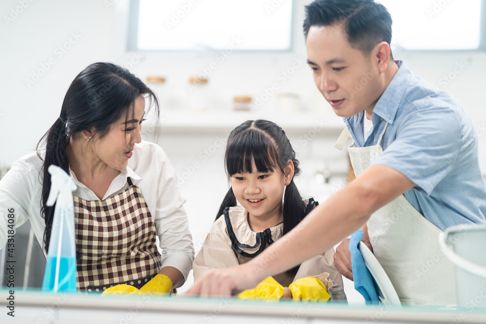 亚洲年轻家庭教女儿清洁厨房柜台。