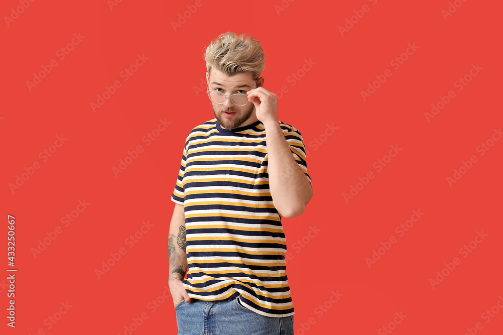 Young man wearing eyeglasses on color background