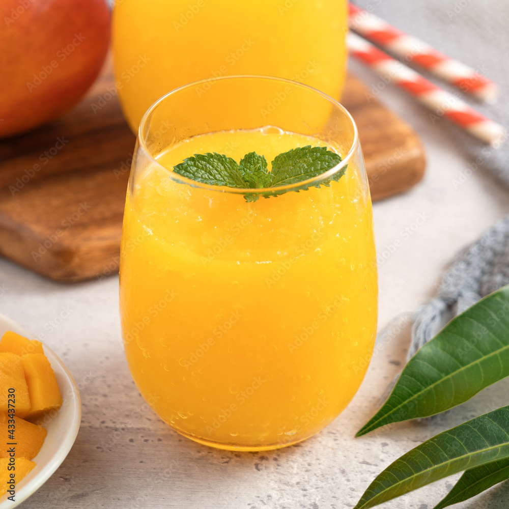 Fresh beautiful delicious mango juice smoothie in a glass cup on gray table background.