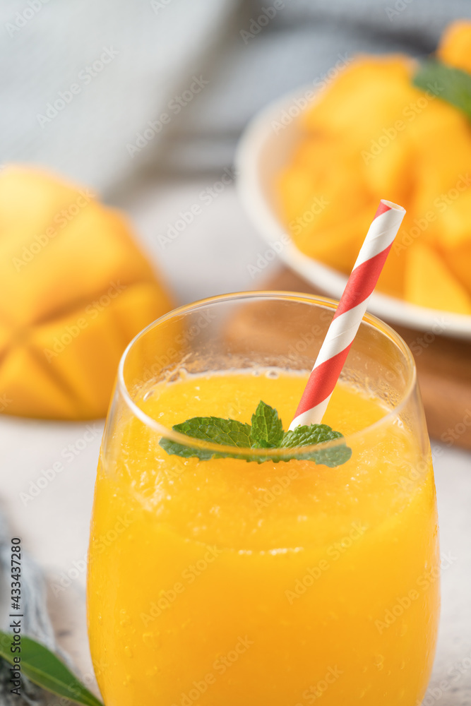 Fresh beautiful delicious mango juice smoothie in a glass cup on gray table background.