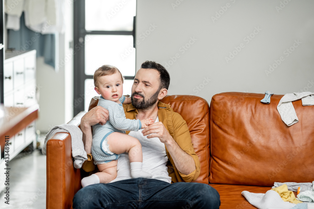 Middle aged dad carrying and playing with newborn baby alone at home. Fatherhood and raising a baby 