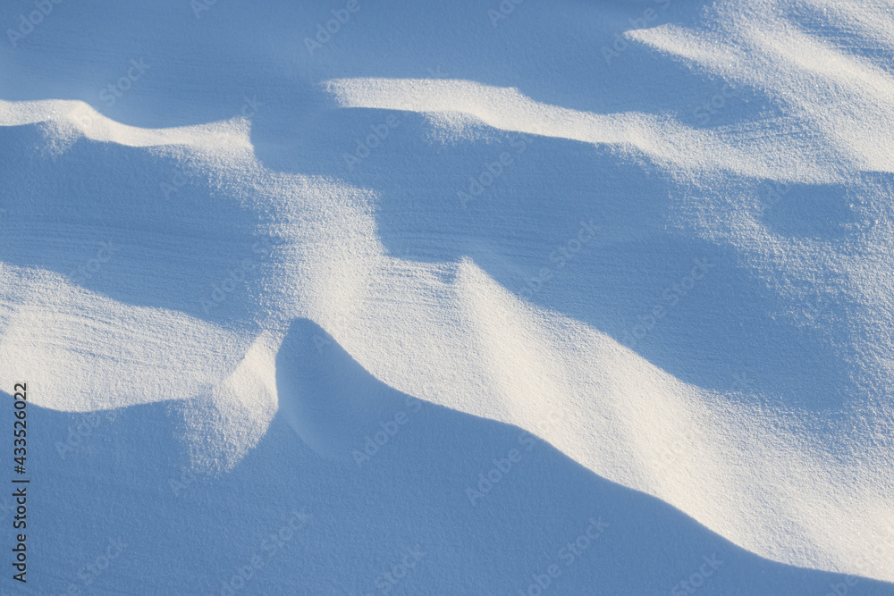 Beautiful winter background with snowy ground. Natural snow texture. Wind sculpted patterns on snow 