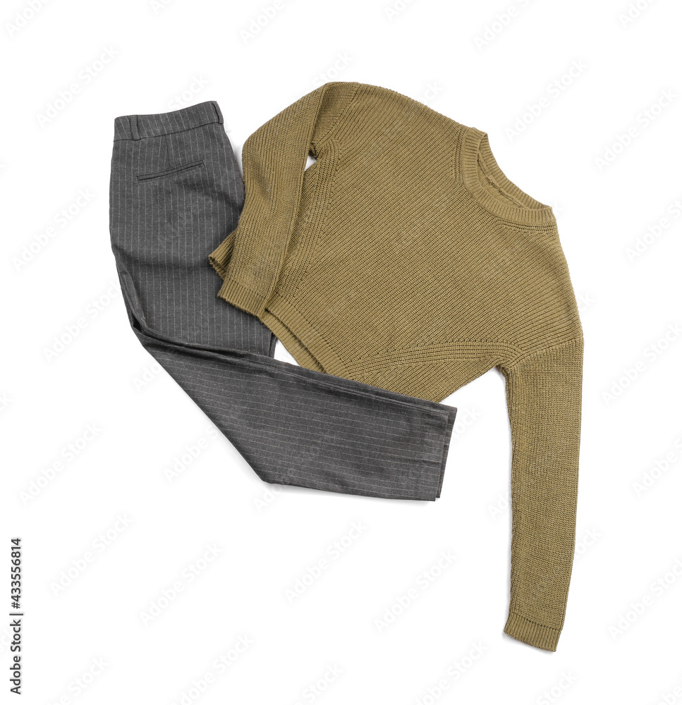 Stylish sweater and trousers on white background