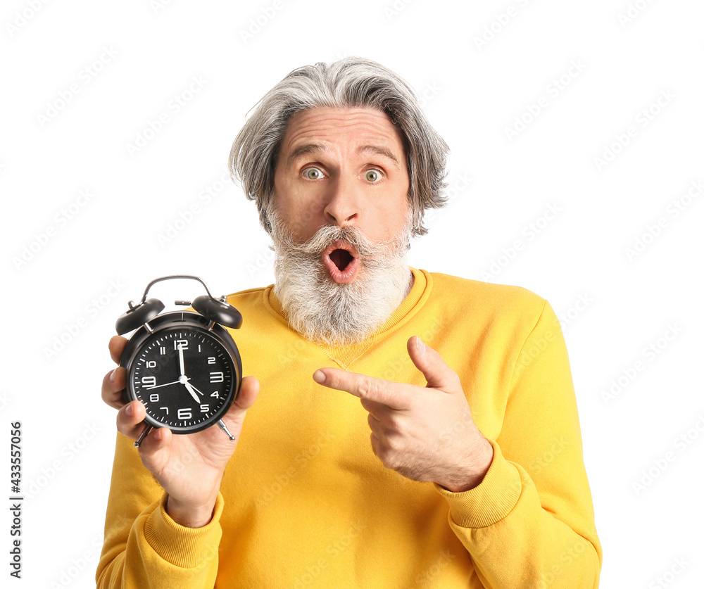 Senior man pointing at alarm clock on white background