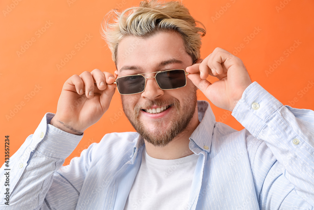 Young man with stylish sunglasses on color background