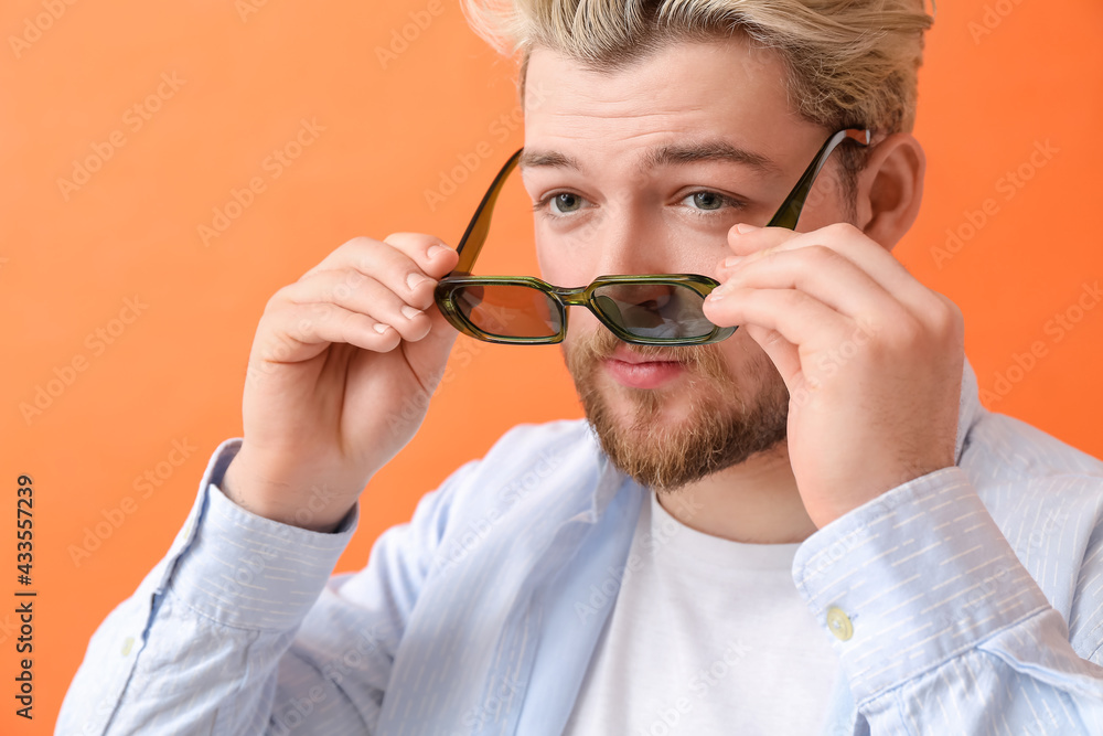 Young man with stylish sunglasses on color background