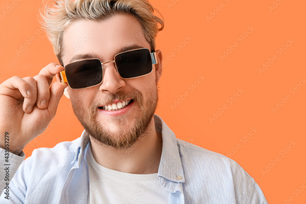 Young man with stylish sunglasses on color background