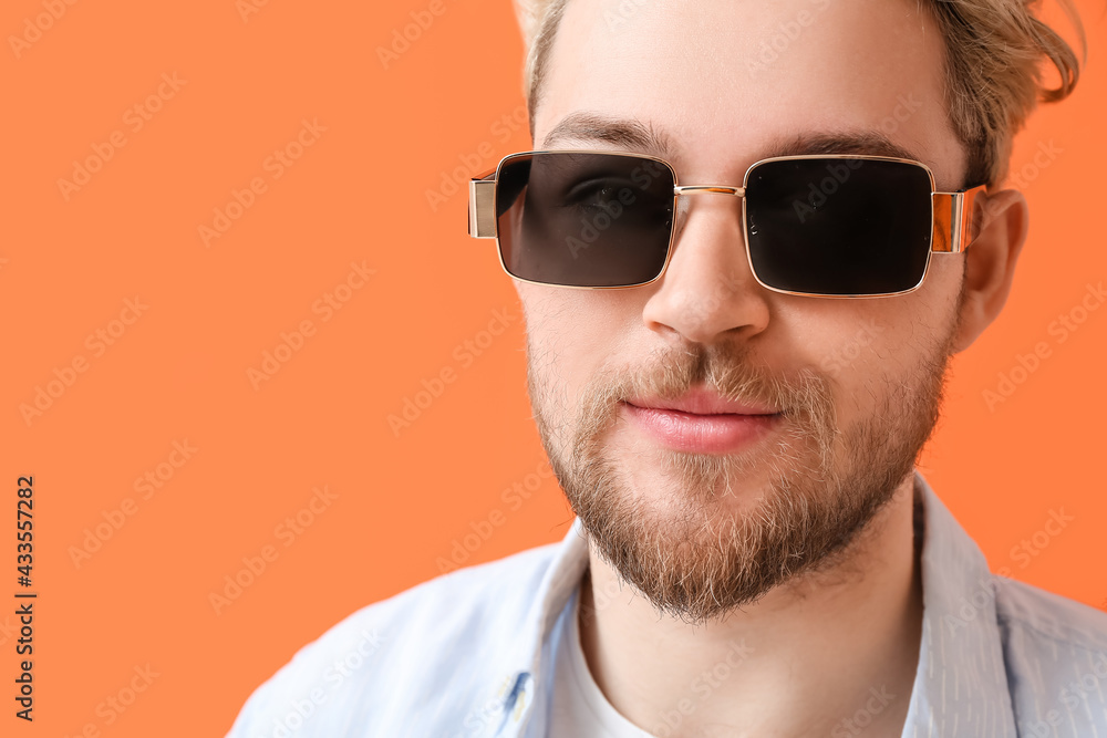 Young man with stylish sunglasses on color background