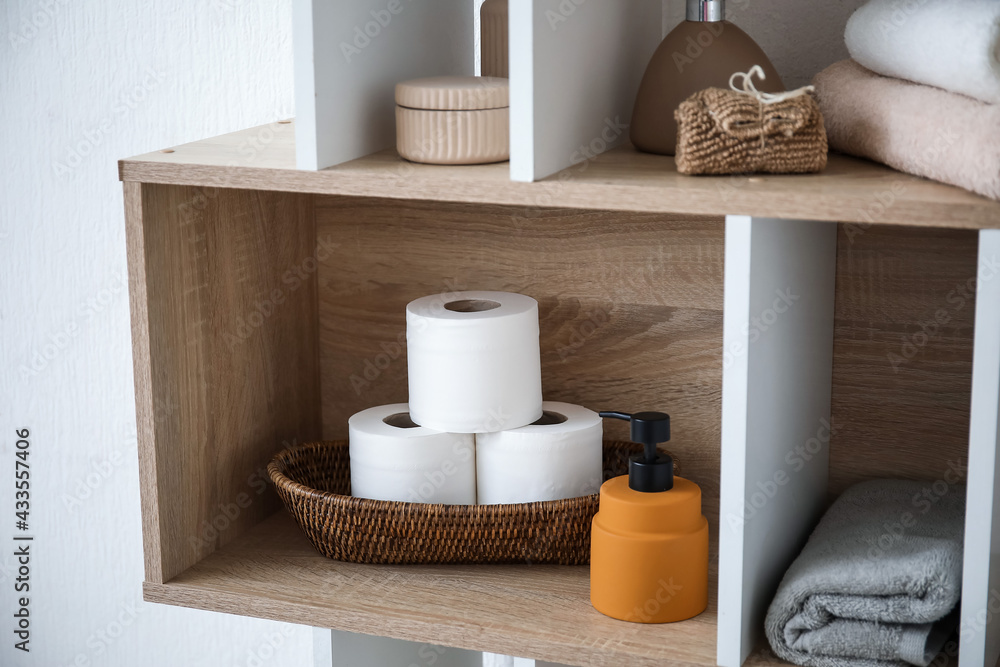 Shelf with rolls of toilet paper and bath supplies in bathroom