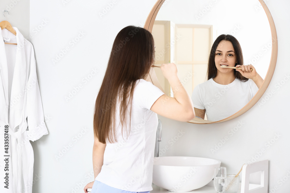 Young woman brushing teeth in bathroom