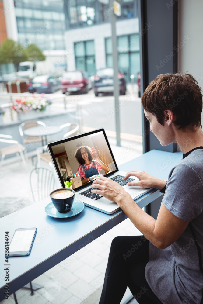 Asian businesswoman sitting at desk using laptop having video call with female colleague