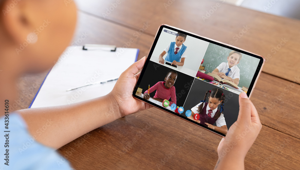 Mixed race businesswoman sitting at desk using tablet having video call