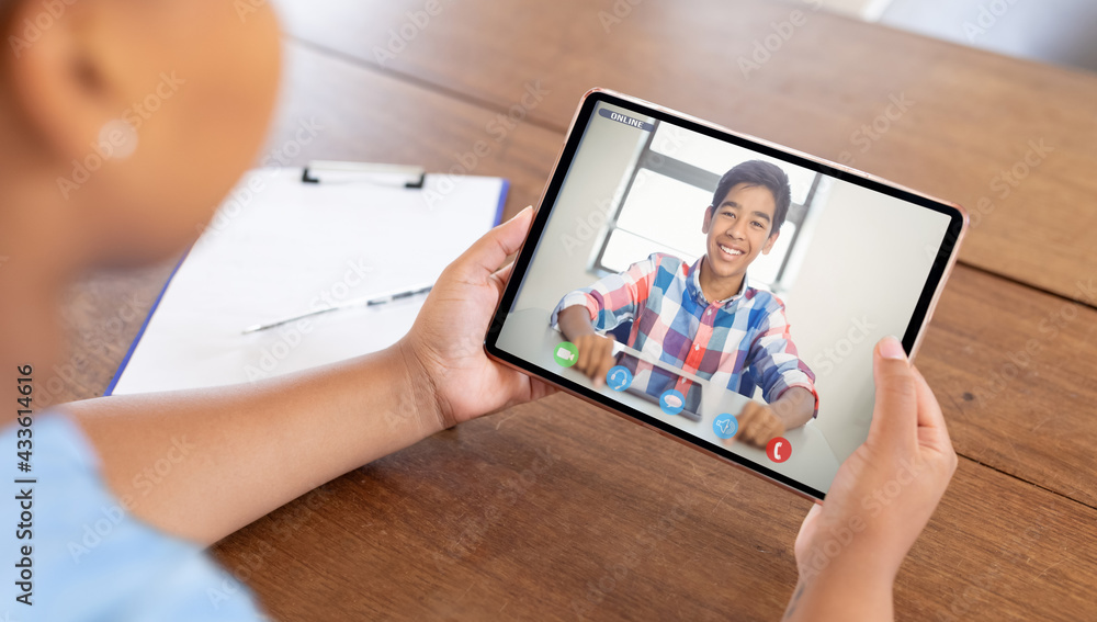 Mixed race businesswoman sitting at desk using tablet having video call