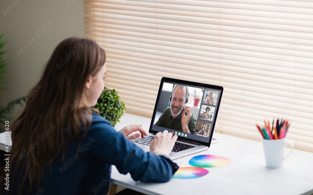 Caucasian businesswoman sitting at desk using laptop having video call with group of colleagues