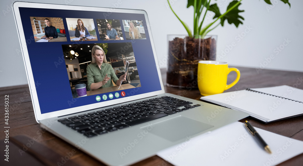 Laptop computer with a video call from businesspeople lying on desk