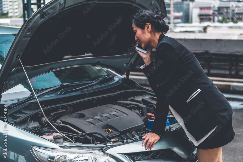 Young businesswoman whose car breakdown uses mobile phone to call for roadside assistance service. T