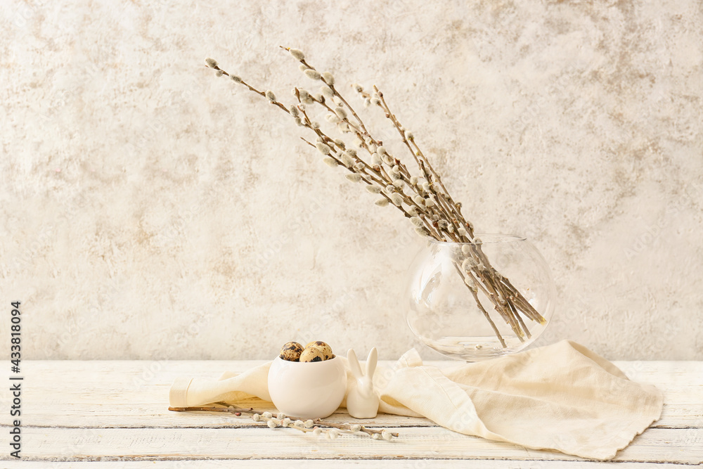 Willow branches and quail eggs on light wooden table