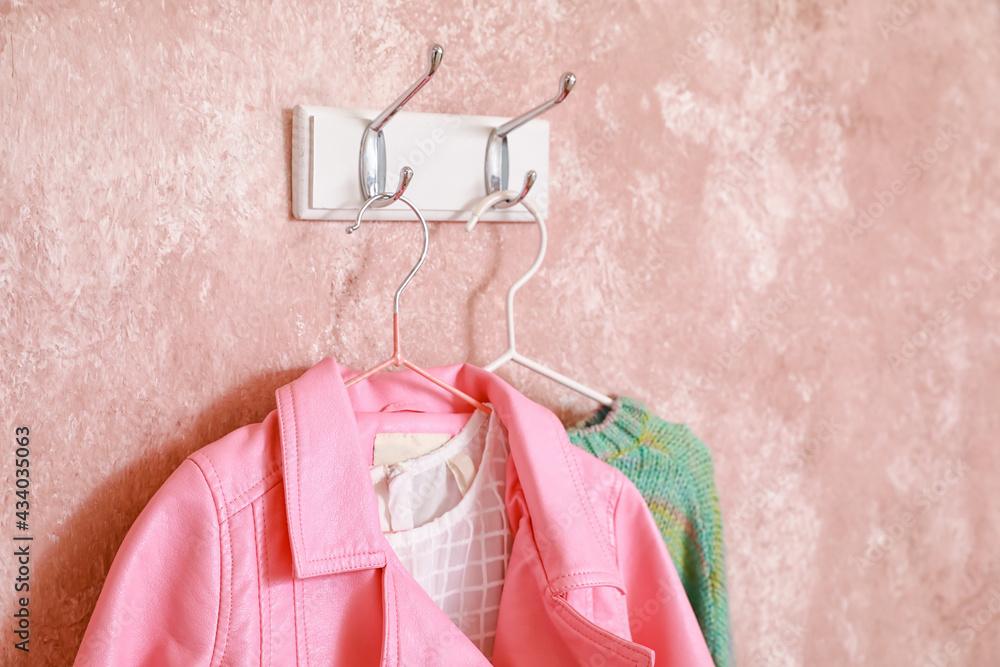 Hanger with stylish clothes on color background, closeup