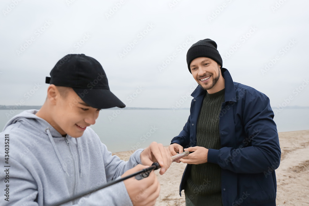 Father and son fishing together on river