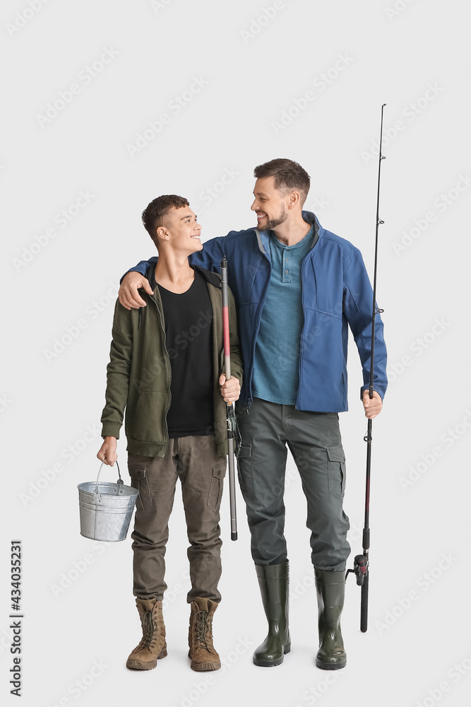 Happy father and son with fishing rods and bucket on white background