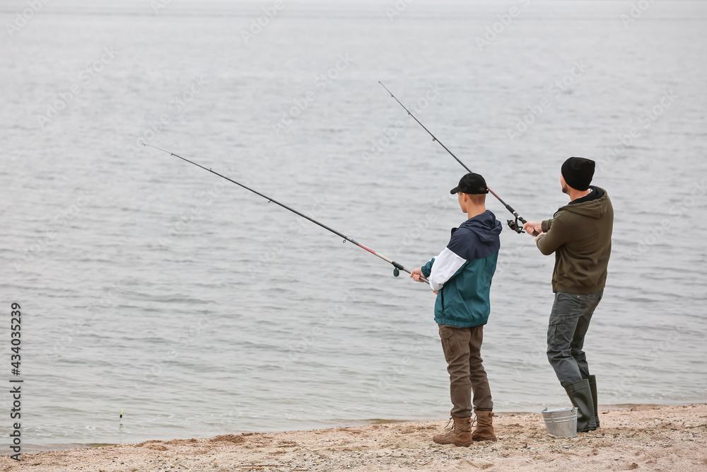 Father and son fishing together on river