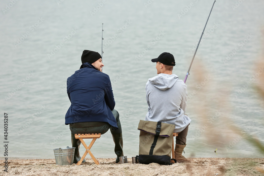 Father and son fishing together on river