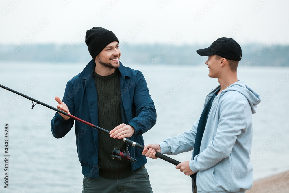 Father and son fishing together on river