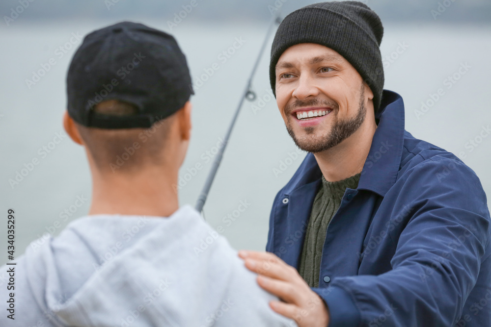 Father and son fishing together on river