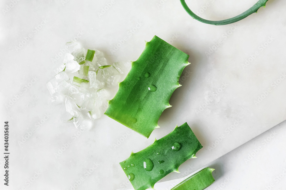 Board with fresh cut aloe on light background