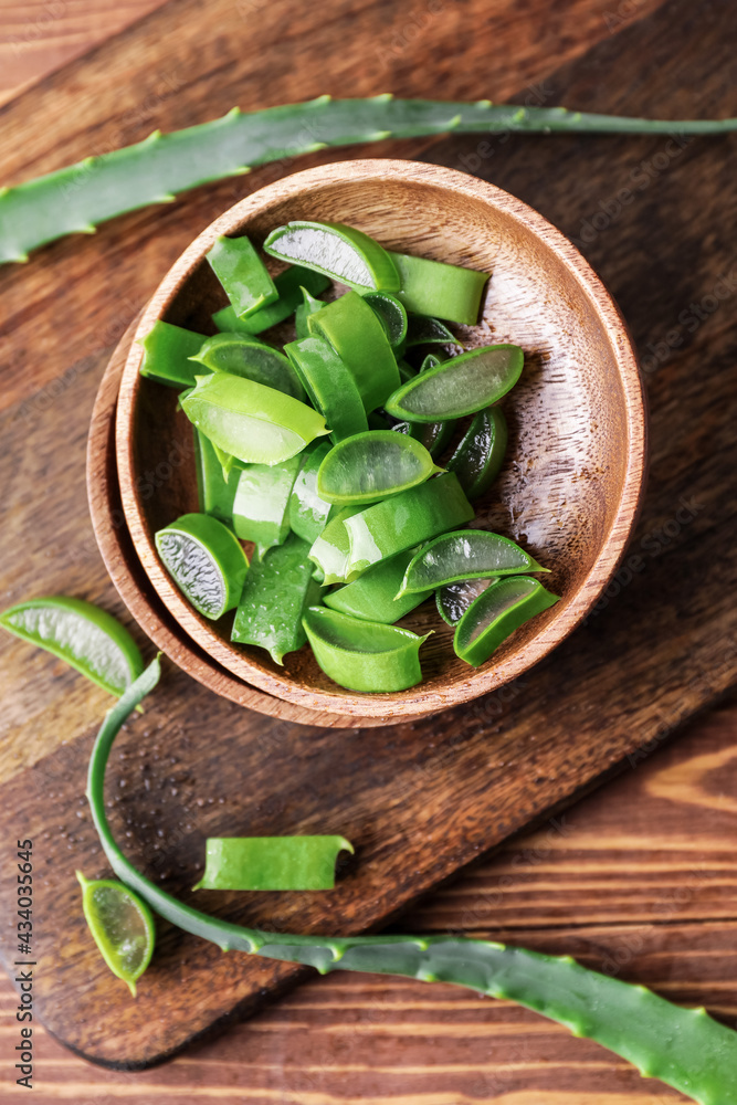 Plates with fresh cut aloe on wooden background