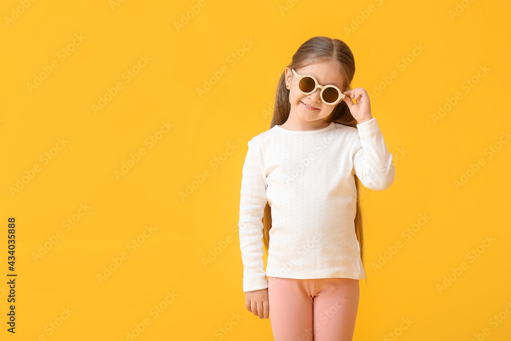 Cute little girl wearing stylish sunglasses on color background