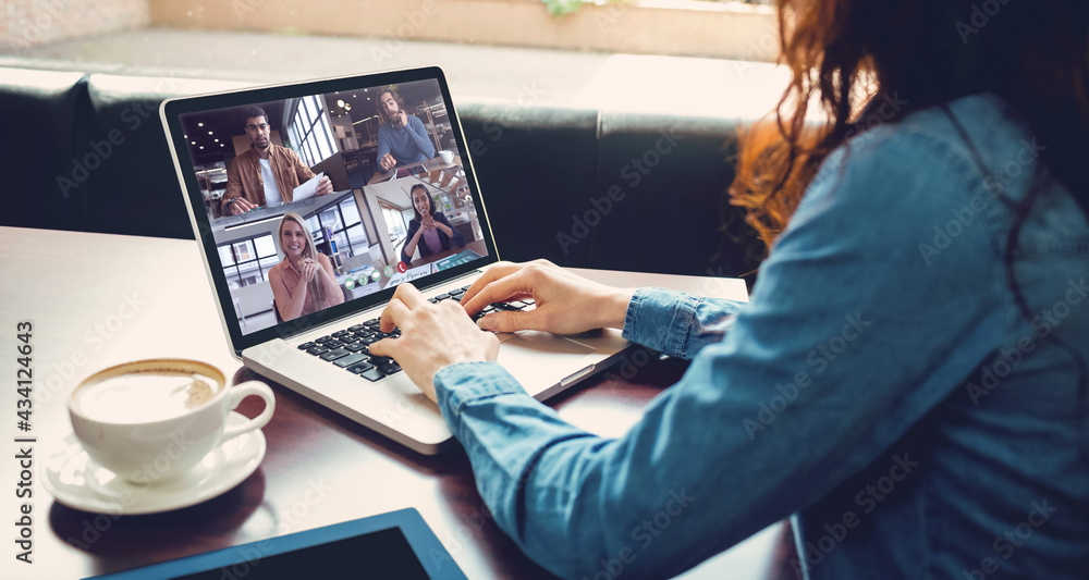 Caucasian businesswoman in cafe using laptop having video call with colleagues