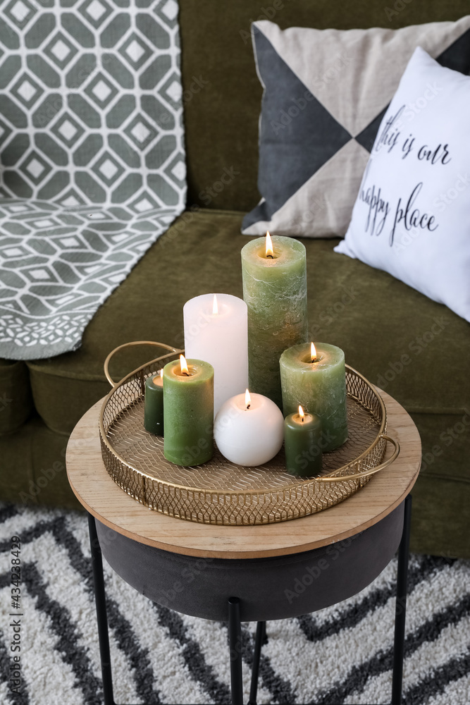 Burning candles on table in interior of stylish living room