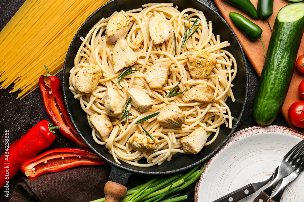 Frying pan with cooked chicken and pasta on table